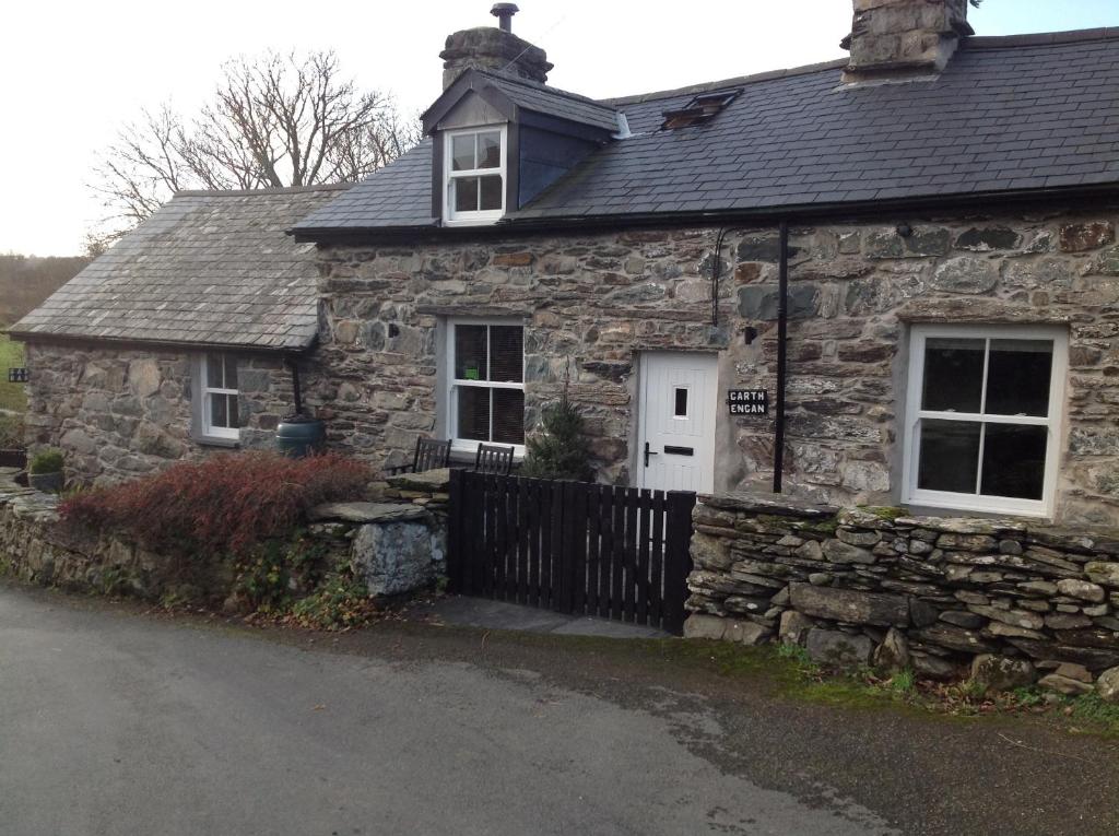 an old stone house with a black fence at Garth Engan Private Self Contained B&B with Garden Area in Llanbedr