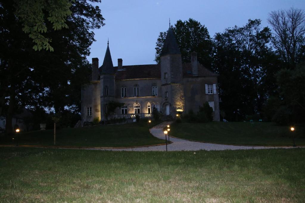 an old castle at night with lights in the grass at château de millery 
