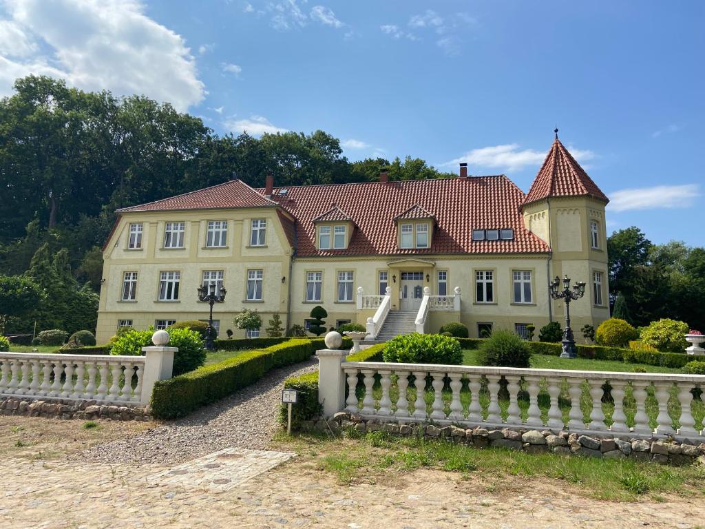 a large yellow house with a white fence at Gutshaus Wohlenhagen in Wohlenberg