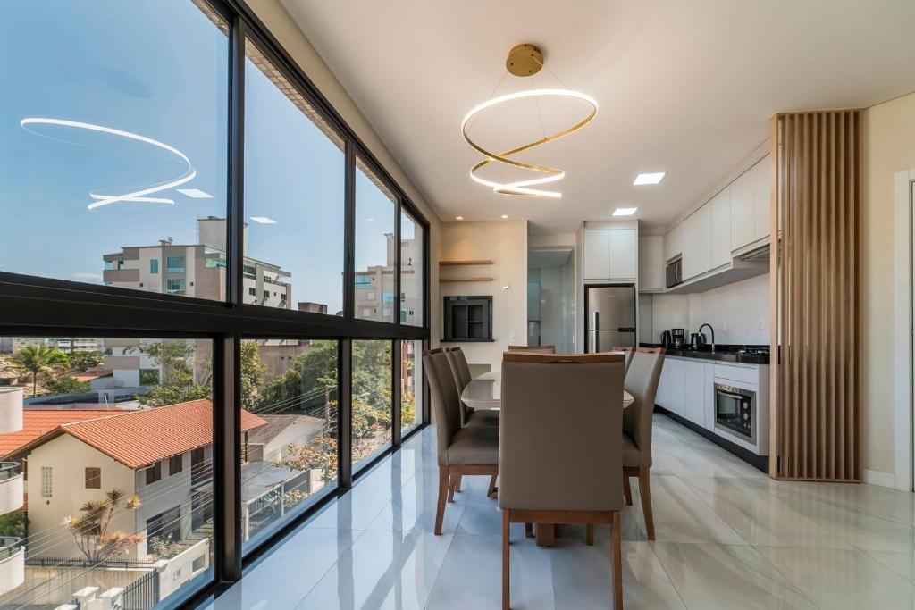 Apartamento 2 suítes em Bombas في بومبينهاس: مطبخ بنوافذ كبيرة وطاولة وكراسي