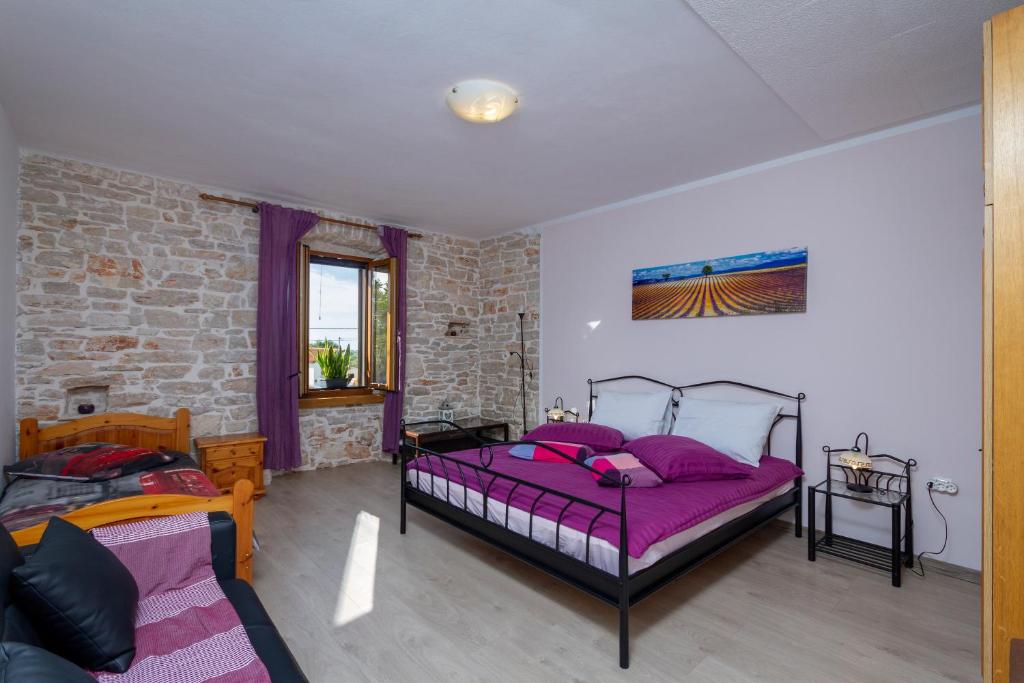 a bedroom with two beds and a brick wall at Holiday stone house in Bale