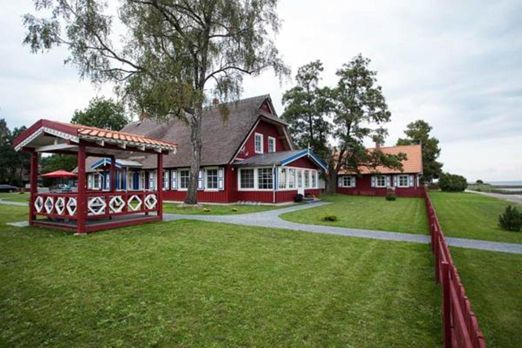 a red house with a fence in front of it at Vila Pervalka in Pervalka