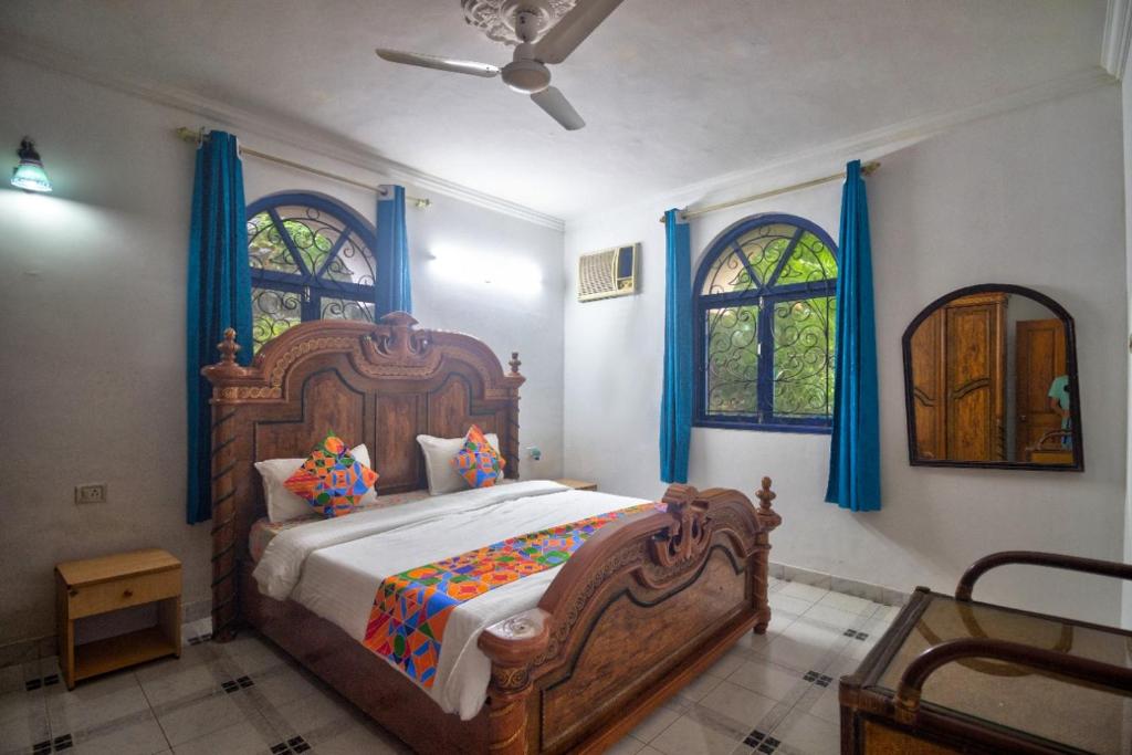 1 dormitorio con cama grande de madera y cortinas azules en Hilltop 4BHK Villa with Private Pool Near Candolim, en Old Goa