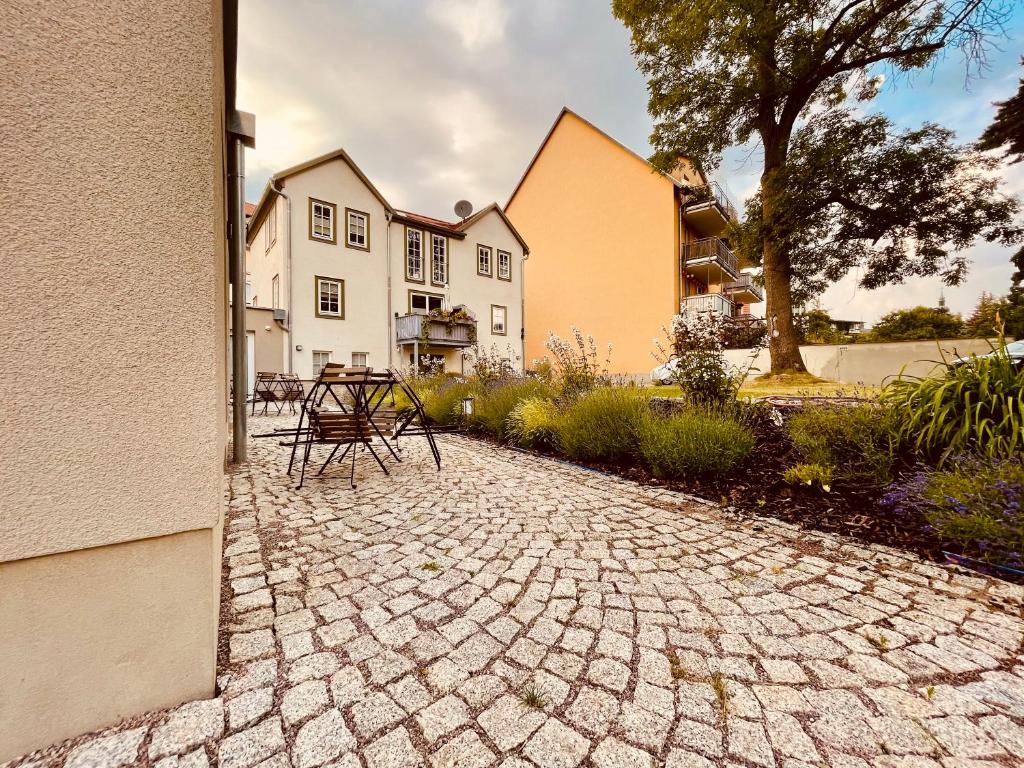 uma mesa e cadeiras sentadas num pátio de pedra em frente a uma casa em Ferienwohnungen Mey Haus zum Rosenstock em Erfurt