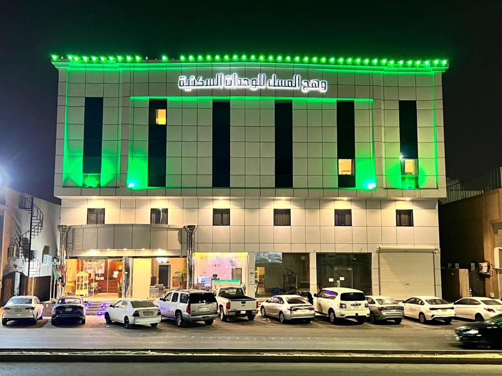 un edificio con coches estacionados en un estacionamiento por la noche en Wahaj Al Mesak Units, en Dammam