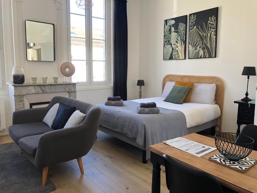 Habitación con 2 camas, sofá y mesa. en Le Studio de Meli, 3 étoiles, 30m2, raffiné, élégant et bien situé, en Rochefort