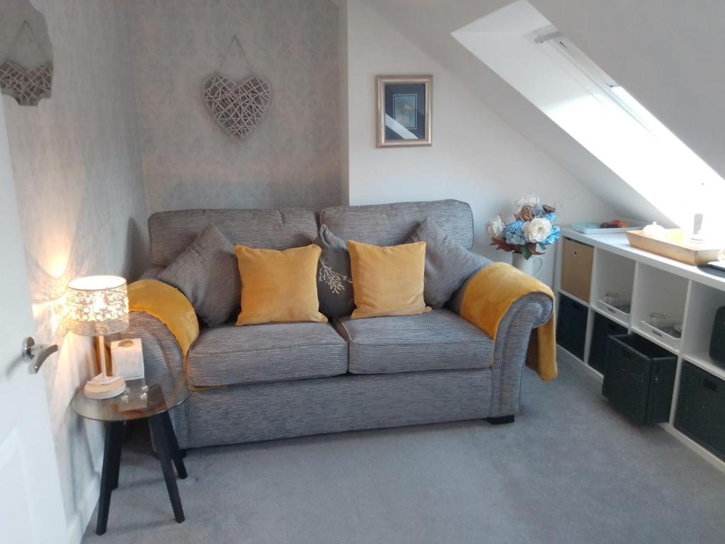 ein Wohnzimmer mit einem grauen Sofa und gelben Kissen in der Unterkunft Village life- Private suite - Living Room, Bedroom and Bathroom in Newtown Saint Boswells