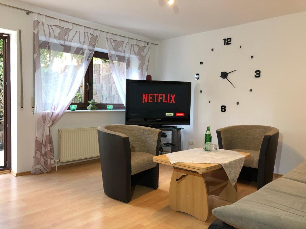 sala de estar con TV y reloj en la pared en Ferienwohnung Familie Hinrichs, en Dorn-Dürkheim