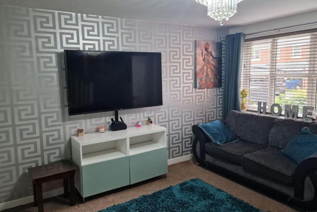 ein Wohnzimmer mit Couch und Flachbildfernseher in der Unterkunft Well Furnished 3 Bedroom House in a cosy estate in Bolton in Bolton