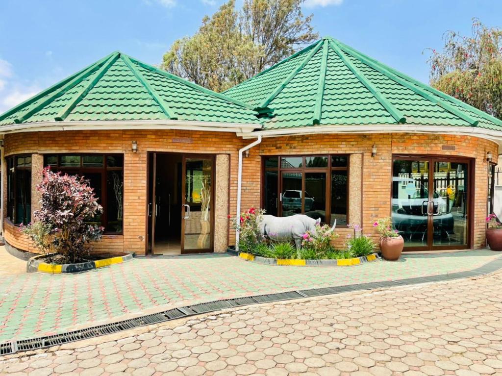 ein Gebäude mit einem grünen Dach mit einem Pferd davor in der Unterkunft Happy Rhino Lodge in Arusha