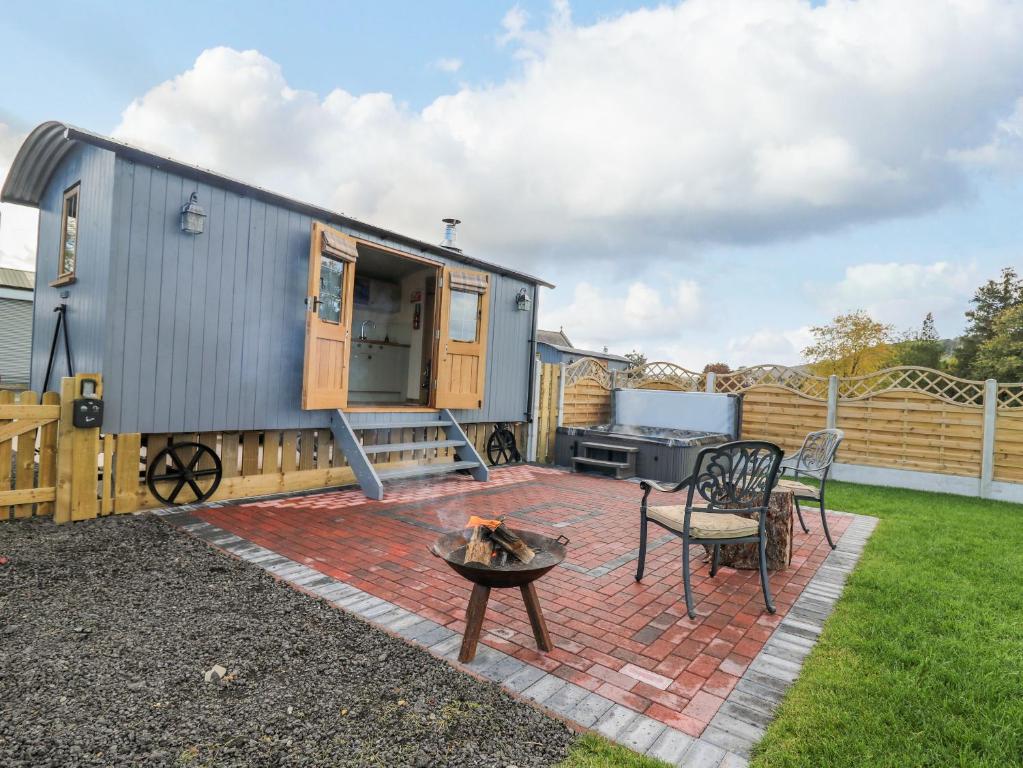 a tiny house on a patio with a fire pit at Poppy in Rhayader
