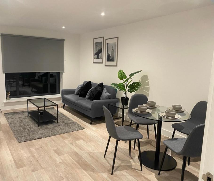 un salon avec un canapé, une table et des chaises dans l'établissement Stylish Birmingham City Centre Apartment, à Birmingham