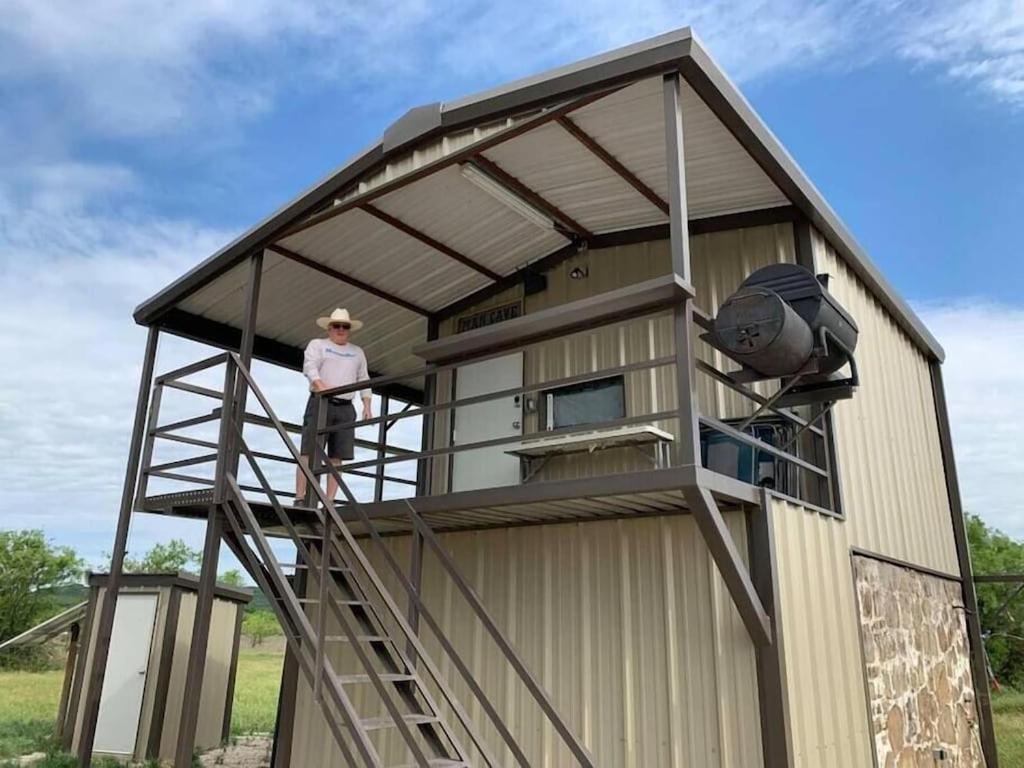 een man op een ladder buiten een klein huisje bij Wilderness Roost on Lake Godstone in Jacksboro