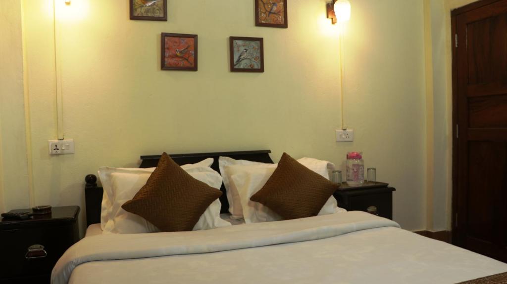 a bedroom with a bed with white sheets and pillows at K & K INN in Cherrapunji