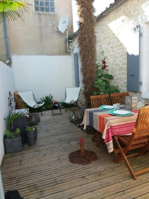 d'une terrasse avec une table, des chaises et un arbre. dans l'établissement Charmante Maison Oléronnaise ALOCEANE, à Saint-Denis-dʼOléron