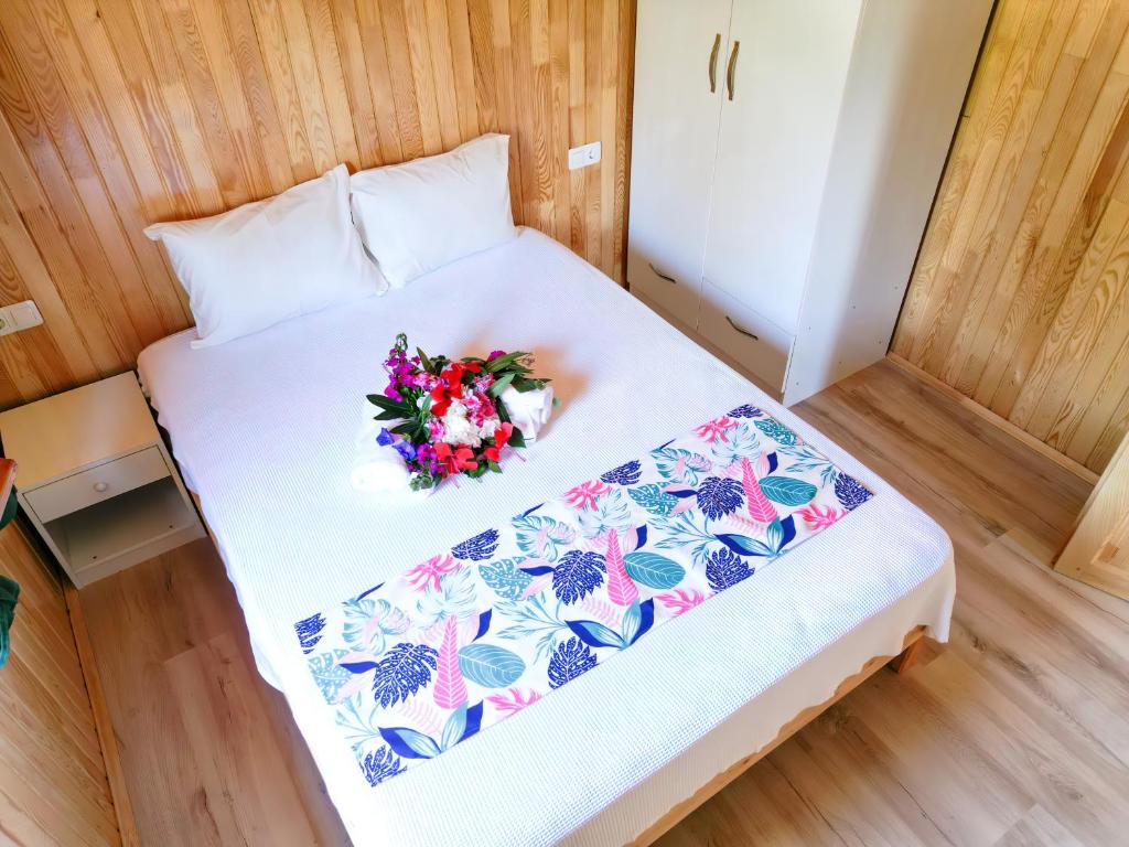 a white bed with a bouquet of flowers on it at Öyküm apart adrasan in Kumluca