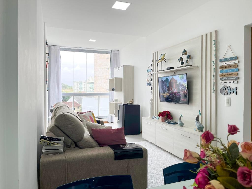 a living room with a couch and a tv at Estada inesquecível 09 Bacutia/Guarapari Premium in Guarapari