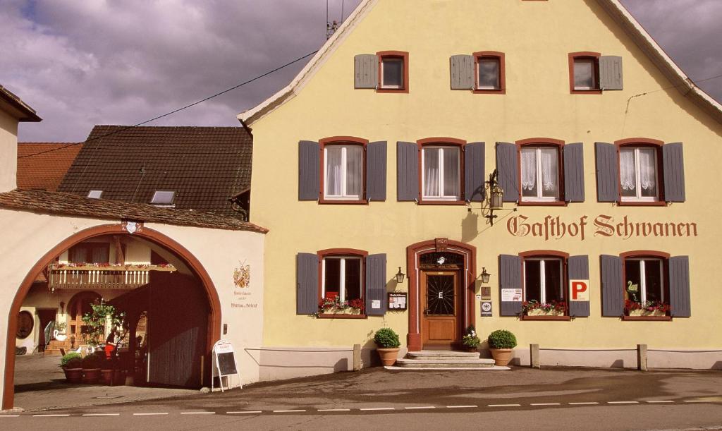 un grande edificio giallo con un cartello sopra di zum Schwanen Garni a Buggingen