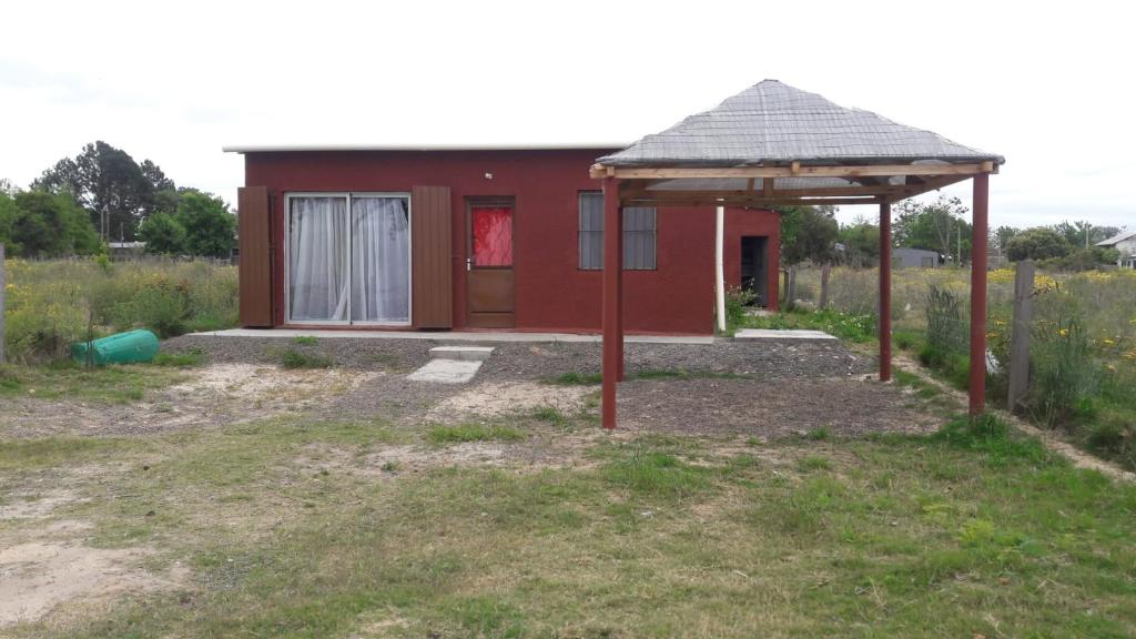 una piccola casa rossa in un campo di Afecto a San Gregorio de Polanco