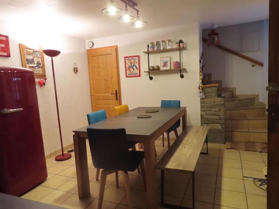 un comedor con mesa y sillas y una escalera en Authentique Maison de Village Savoyarde, en Saint-Martin-de-Belleville