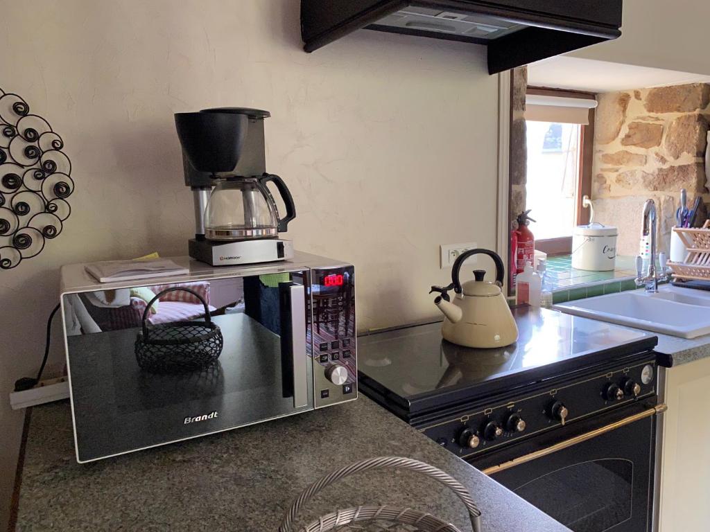 a kitchen with a coffee maker on top of a microwave at Gîte Maison Maitri in Forgès