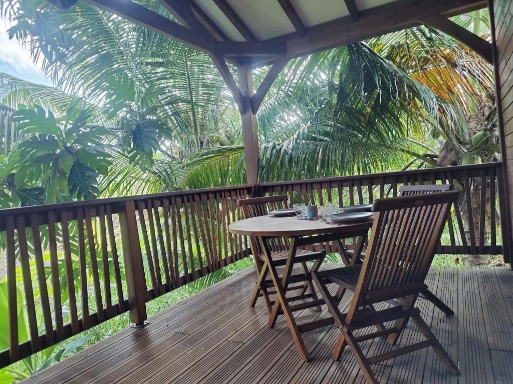 uma mesa e cadeiras num deque com palmeiras em Coco et Cajou Bungalows em Sainte-Anne