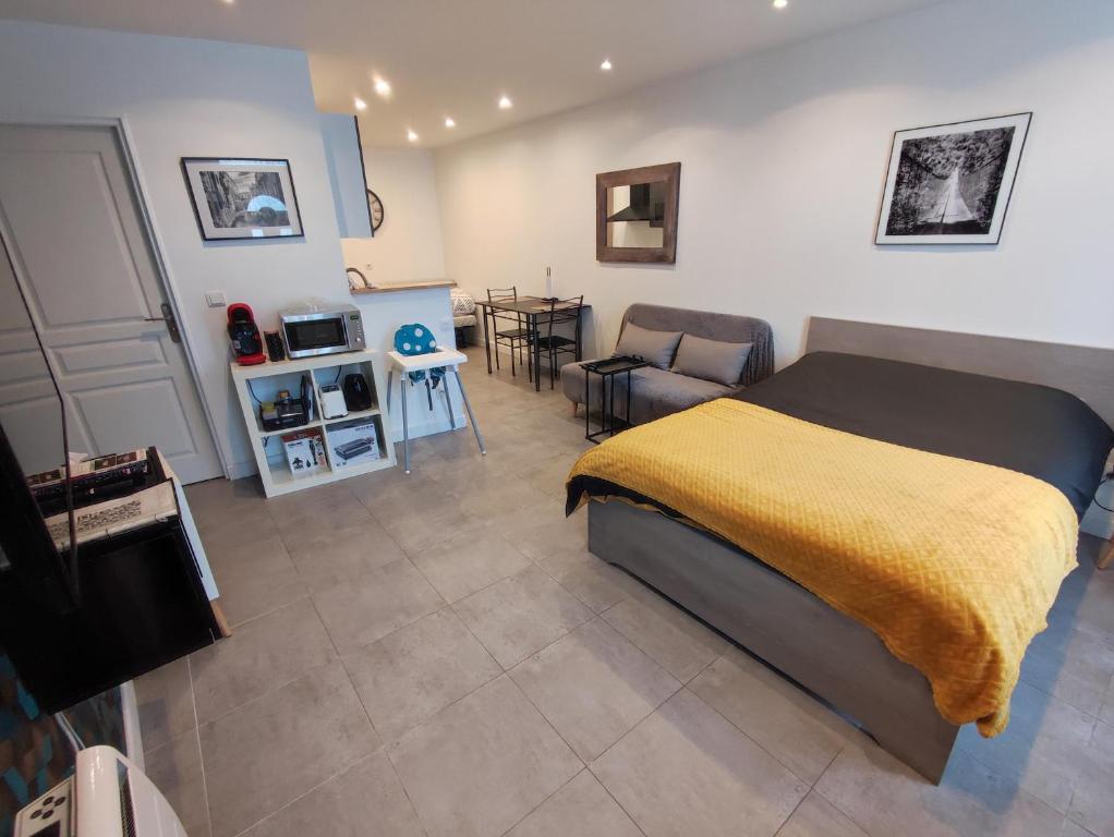 Un dormitorio con una cama con una manta amarilla. en Studio Autonome Cosy à Paris CDG en Vaudherland