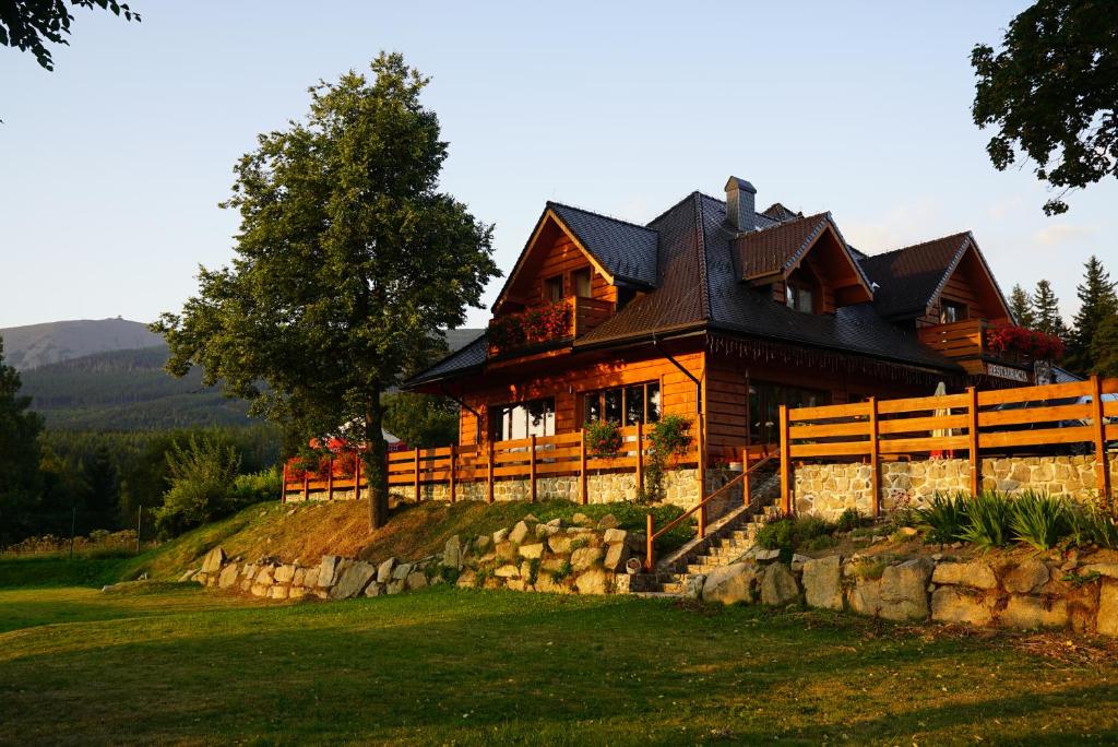 ein großes Holzhaus auf einem Hügel mit einem Zaun in der Unterkunft Pensjonat Pod5 in Karpacz