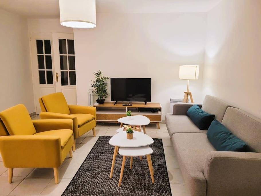 uma sala de estar com um sofá e cadeiras e uma televisão em Casteljaloux Appartement 2 chambres balcon parking résidence calme em Casteljaloux