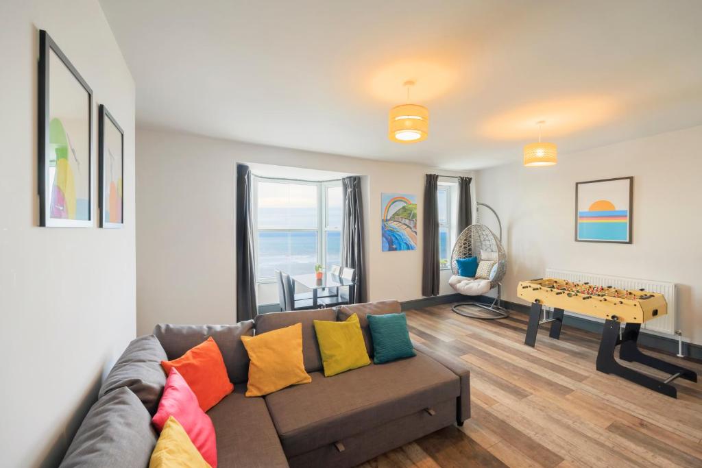 ein Wohnzimmer mit einem Sofa und bunten Kissen in der Unterkunft Seafront apartment with balcony, parking and sea views in Aberystwyth