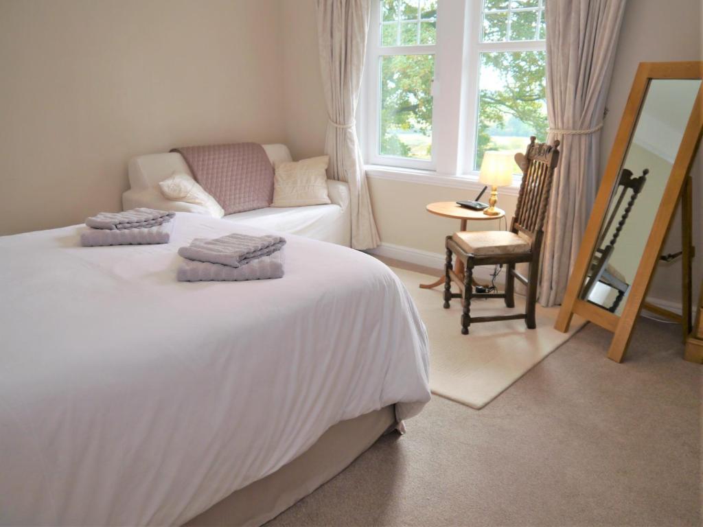 a bedroom with a bed and a chair and a mirror at Glaisters Farmhouse in Castle Douglas