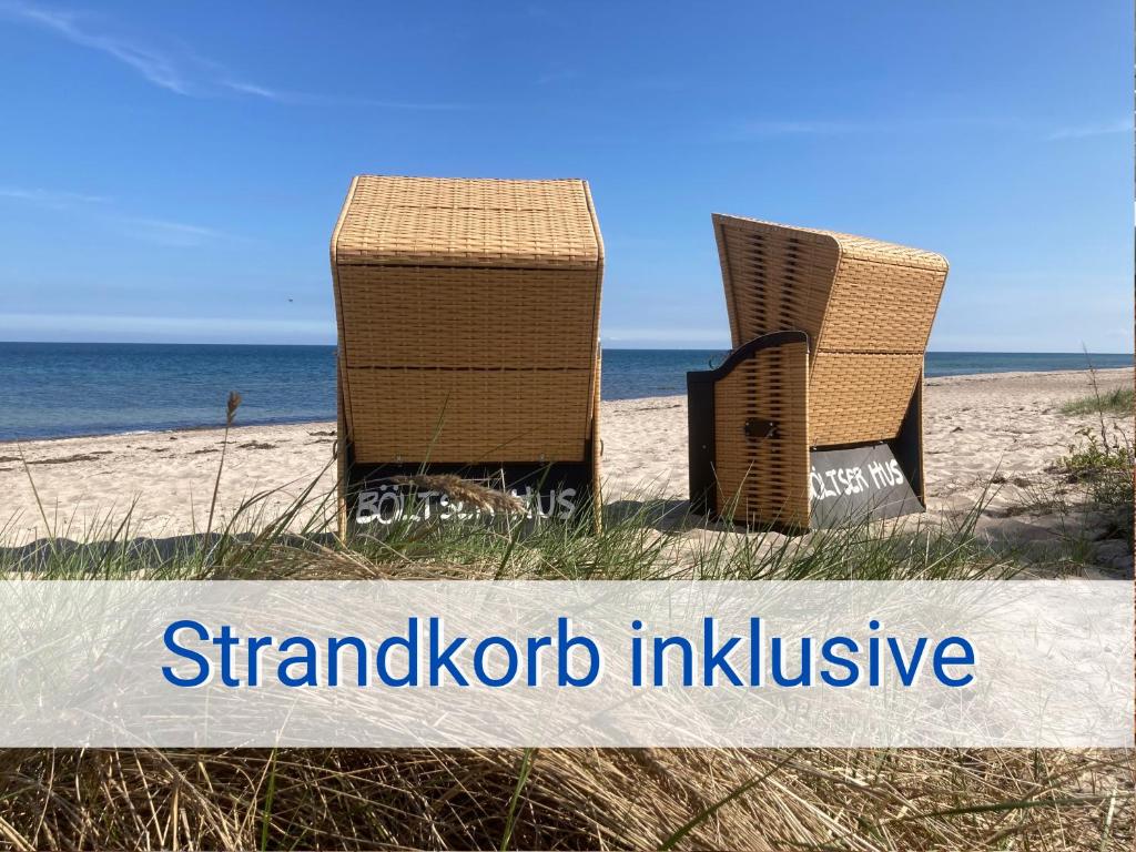 two chairs sitting on the beach near the ocean at Böltser Hus Ferienwohnungen mit Strandkorb und Kamin 10 Gehminuten zum kurtaxefreien Sandstrand in Neukirchen