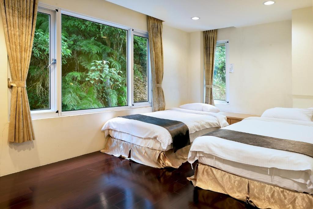 - 2 lits dans une chambre avec une grande fenêtre dans l'établissement Sun Moon Lake Karuizawa Villa, à Yuchi