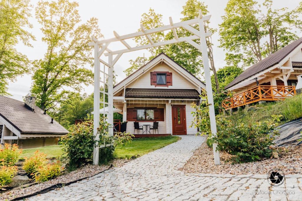 ein Haus mit einer weißen Pergola davor in der Unterkunft Domki Cicha Struga in Chocieszow