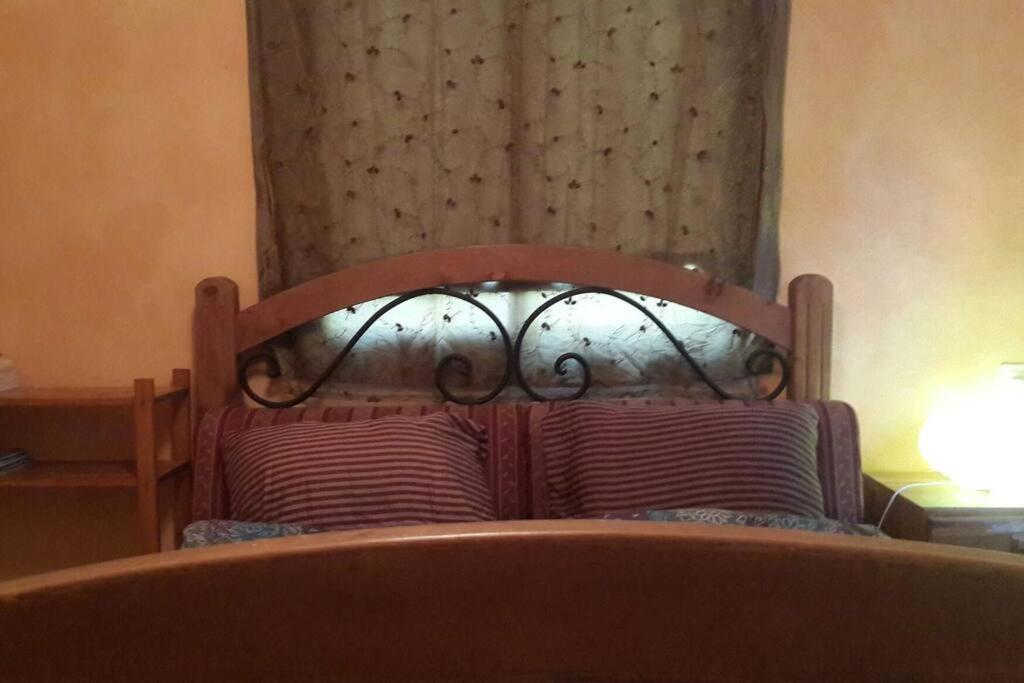 a bed with a wooden headboard and a curtain at negev ein habsor עין הבשור דרום in Ein HaBesor