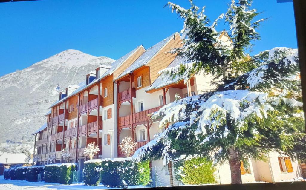 un edificio en la nieve con una montaña en el fondo en Appartement Duplex dans Résidence VAL DE ROLAND en Luz-Saint-Sauveur