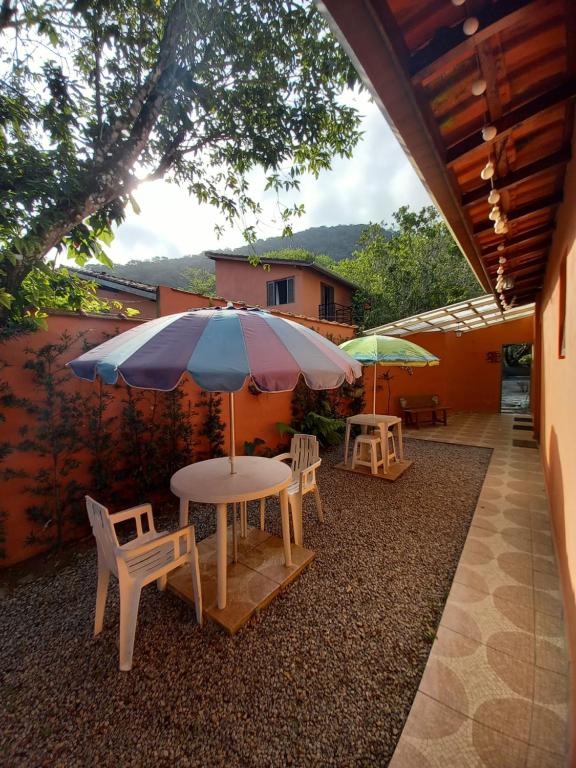 einen Tisch und Stühle mit Sonnenschirm auf einer Terrasse in der Unterkunft SUÍTES ITABERABA BOIÇUCANGA in Boicucanga