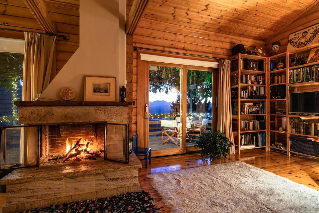 a living room with a fireplace and a book shelf at Luxury Chalet Vila on Mountain Top with great view in Kalavrita