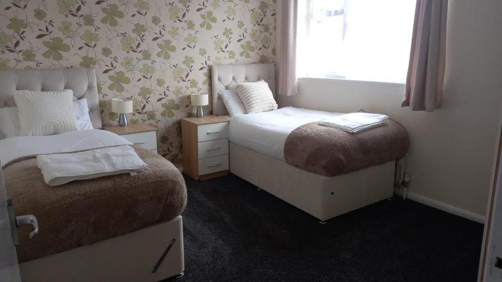 a small bedroom with two beds and a window at Hamble Lounge - Accomodation for Aylesbury Contractors & Industrial estate - Free Parking & WIFI Sleeps up to 6 people in Buckinghamshire