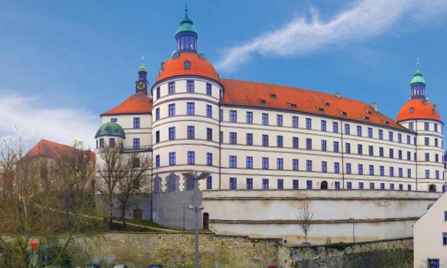 ein großes weißes Gebäude mit rotem Dach in der Unterkunft Neuburg New Apartement in Neuburg an der Donau