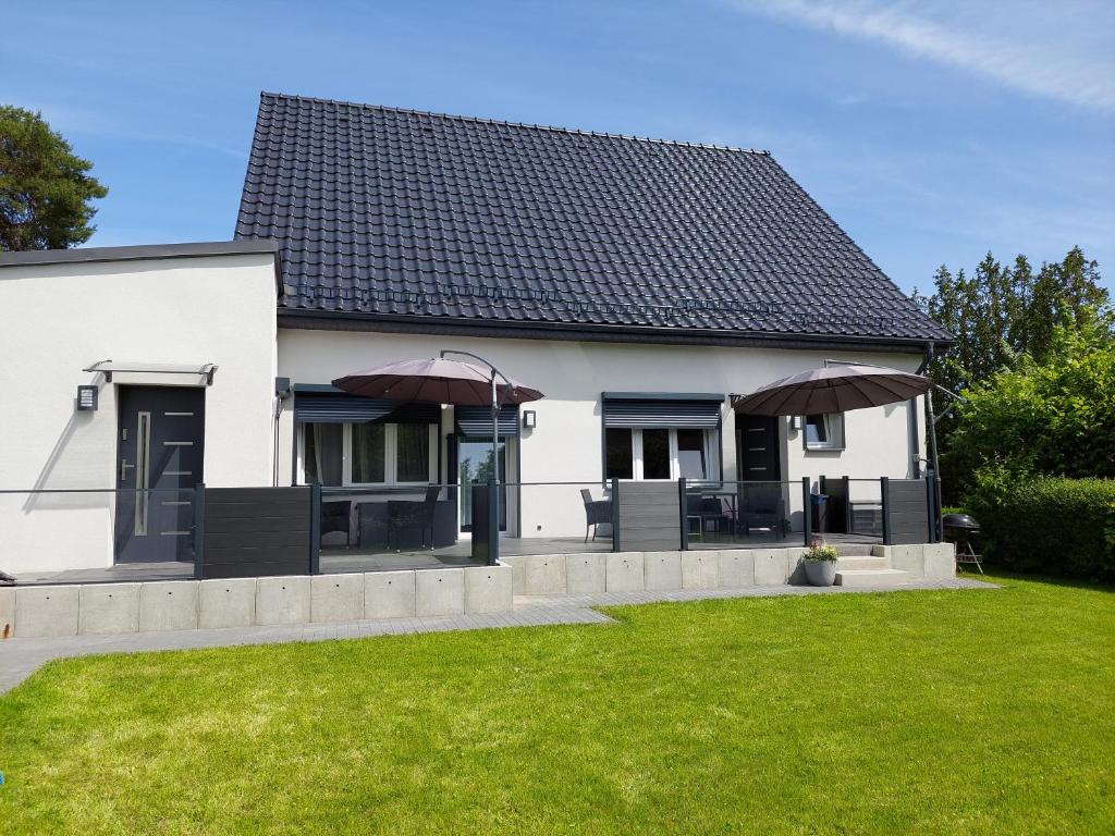 a white house with two umbrellas in a yard at Apartamenty Nowielice in Nowielice