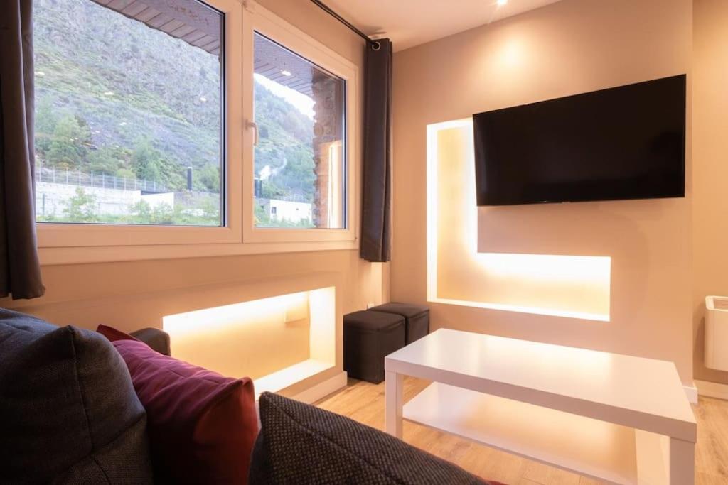 sala de estar con sofá, mesa y TV en Lovely quiet apartment walking distance ski runs, en Soldeu