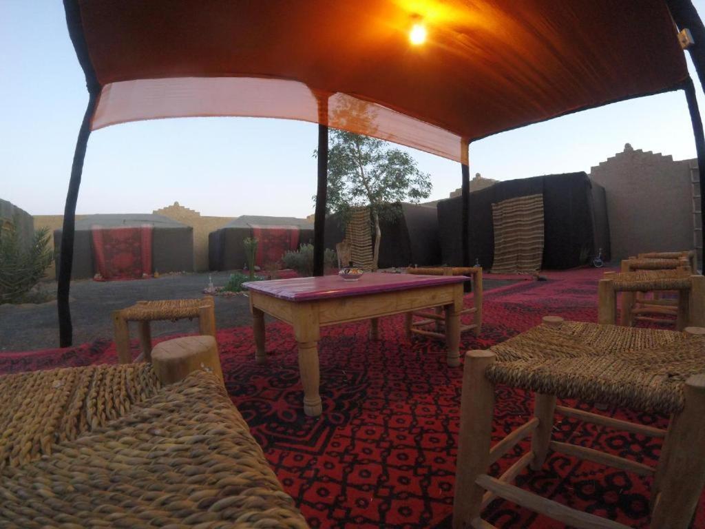 uma tenda com uma mesa e cadeiras num quarto em Nomad Bivouac em Merzouga