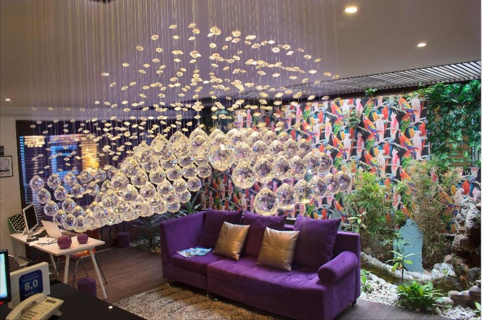 ein Wohnzimmer mit einem lila Sofa und einer Wand aus Weingläsern in der Unterkunft HOTEL BOUTIQUE CASA LOZADA in Bogotá