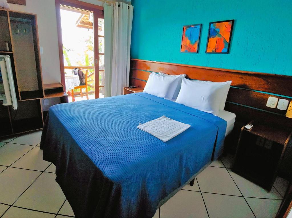 a bedroom with a bed with a blue blanket at Pousada Aquarela do Mar in Abraão