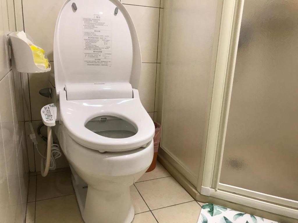 a bathroom with a toilet with the lid up at Kinmen Old Town Homestay in Jincheng