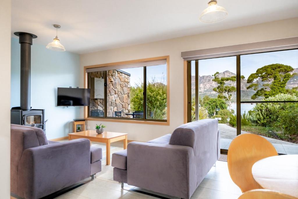 a living room with a couch and chairs and windows at Freycinet Stone Studio 3 - Feldspar in Coles Bay