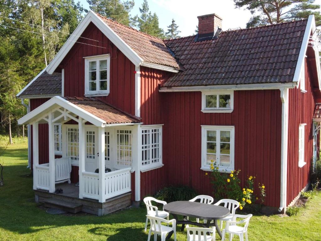 a red house with a table and chairs in the yard at Holiday home GRÄSTORP in Grästorp