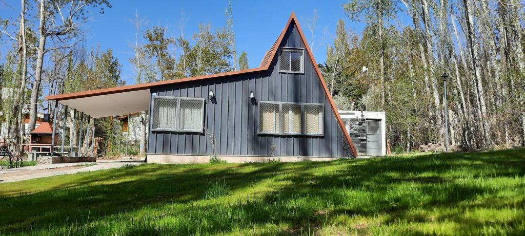 a black house with a red roof on top of a yard at Entre Cardos y Nieves in Potrerillos