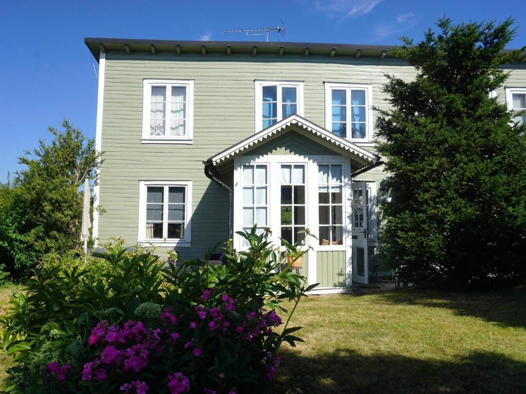 a green house with white windows and purple flowers at Holiday home RONNEBY IX in Ronneby